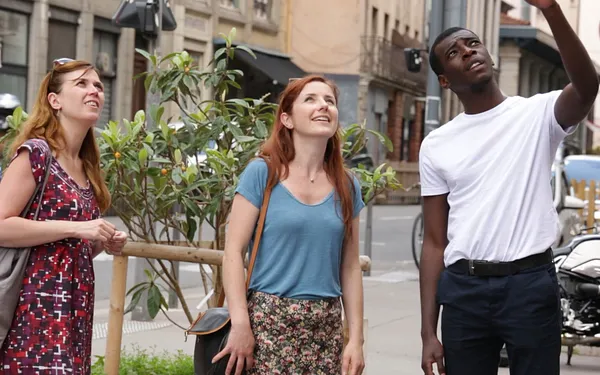 Three French actors look off screen at a mural